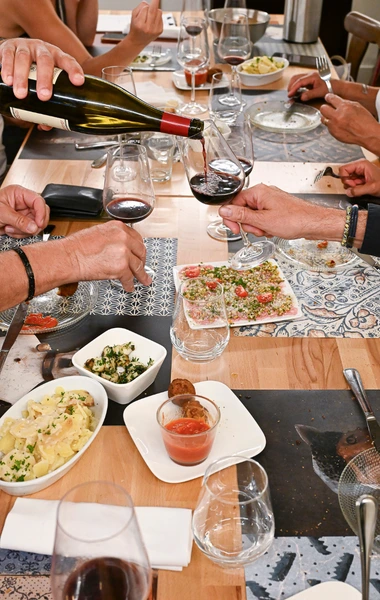 Convives trinquant autour d'une table garnie de plats à partager au restaurant Les Platanes.